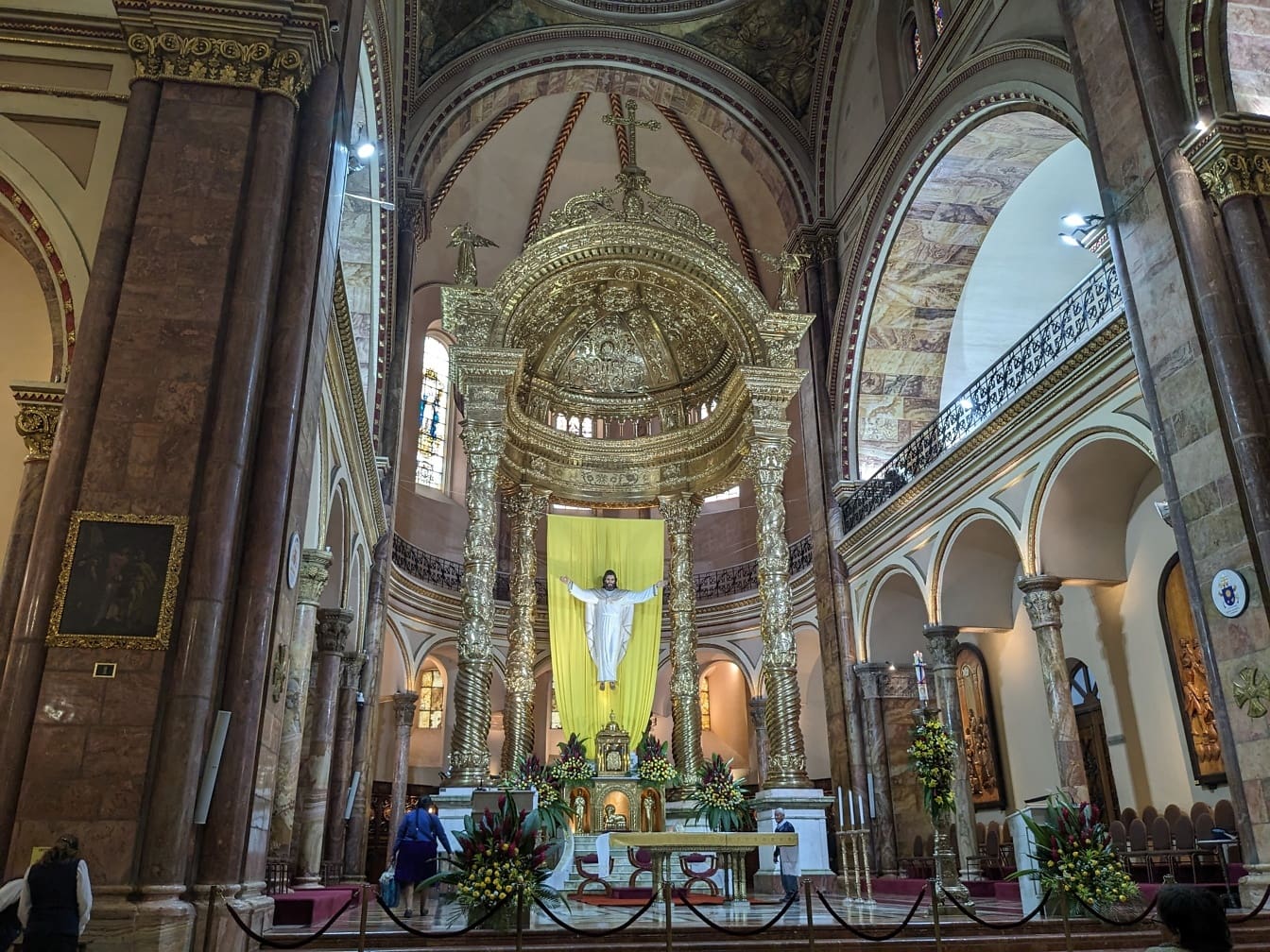 Stort gyllene utsmyckat altare med en staty av en Jesus Kristus i den nya katedralen i Cuenca i Ecuador