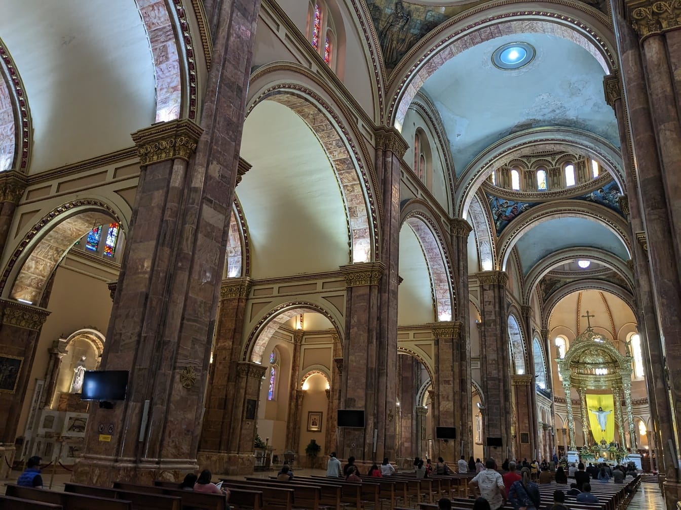 Intérieur de la nouvelle cathédrale de Cuenca en Équateur avec des arcs et un grand autel en or