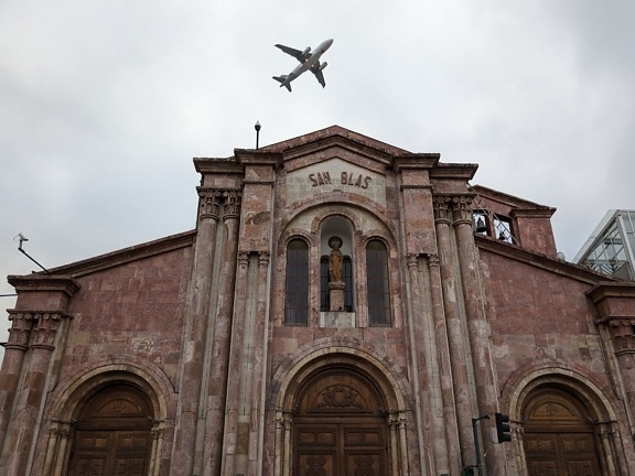 An airplane flying over a catholic church of San Blas in city of Cuenca in Ecuador