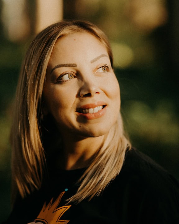 Portrait of a woman with blond hair smiling as the sun’s rays fall on her pretty face