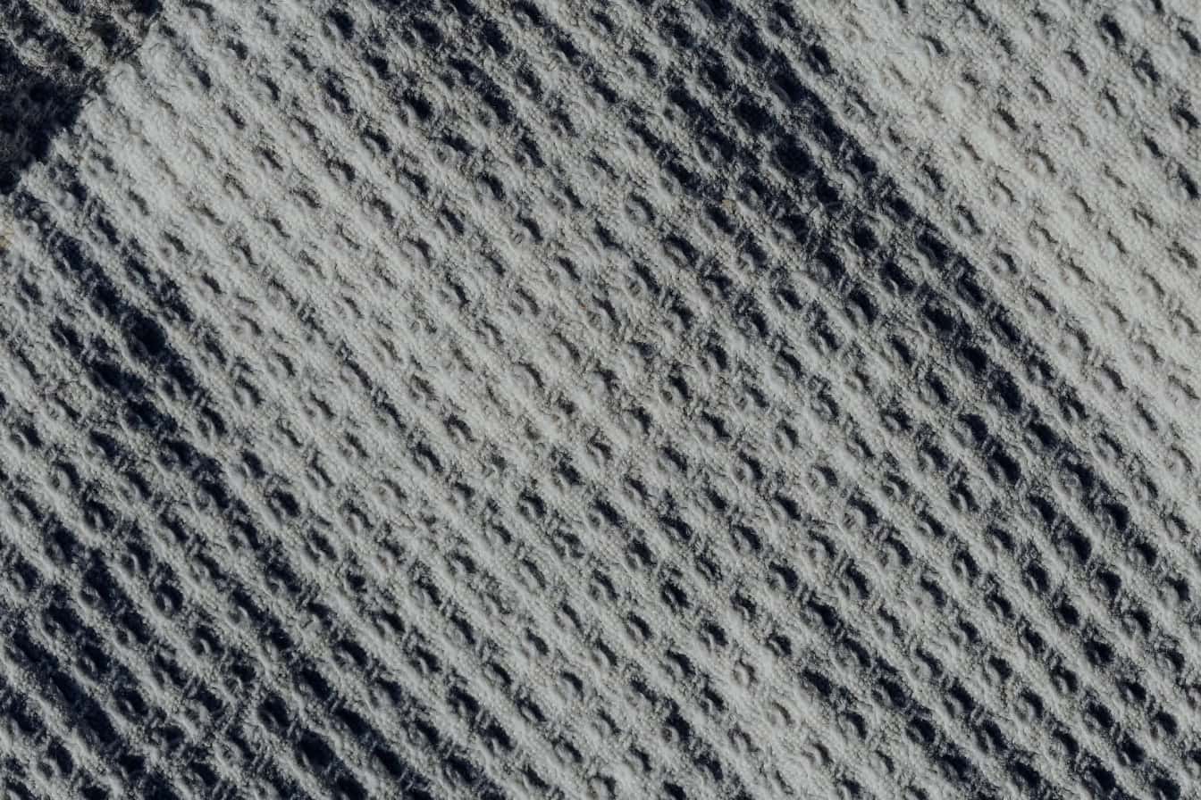 พื้นผิวของผ้าสีเทาที่มีลวดลายเรขาคณิตสี่เหลี่ยมผืนผ้า