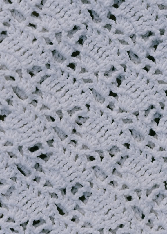 Close-up texture of a white knitted fabric with hand embroidery