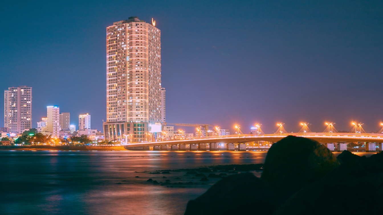 Панорама городского пейзажа мегаполиса с освещенным мостом и ночными небоскребами