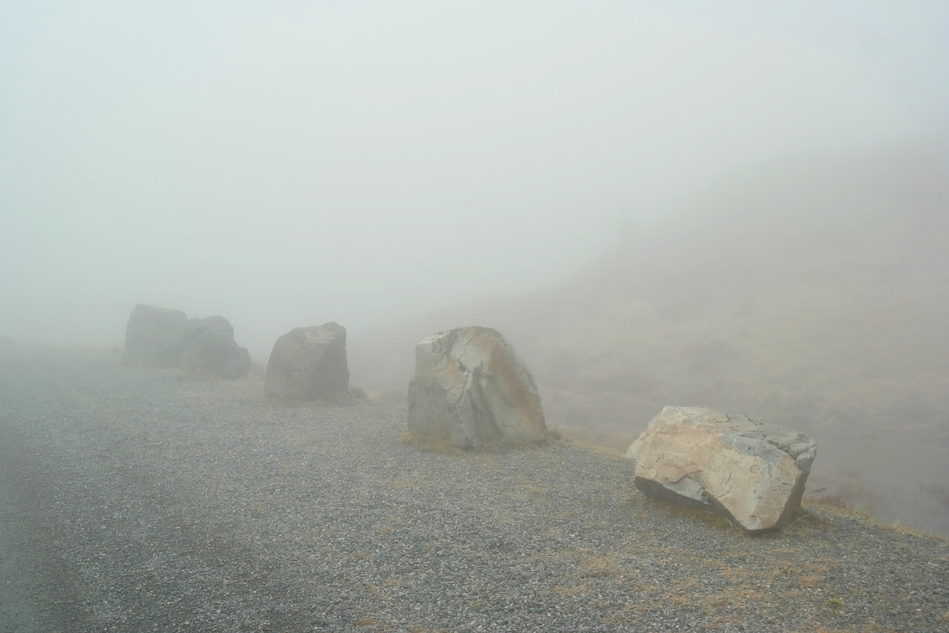 Batu-batu besar di tepi jalan dalam kabut yang sangat tebal