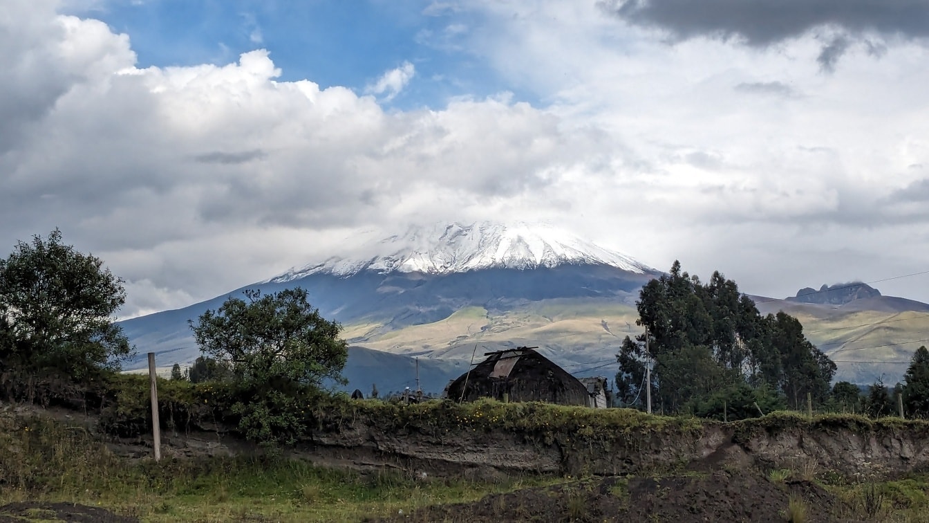 En låve i Andesfjellene i Ecuador med vulkanen Cotopaxi med en snødekt topp i bakgrunnen