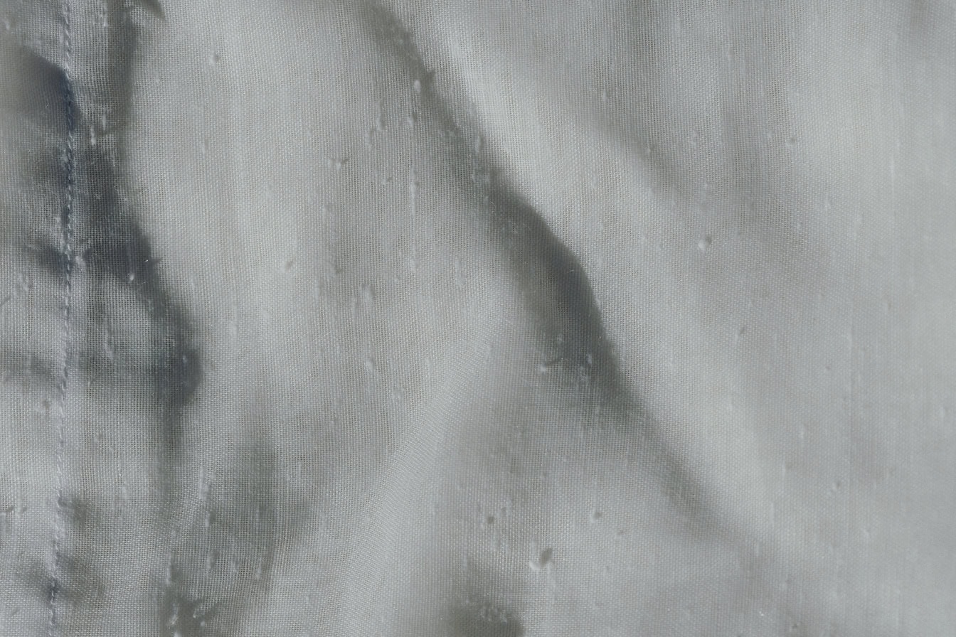 Tekstur av tynt og halvtransparent rent hvitt vattert stoff med bretter