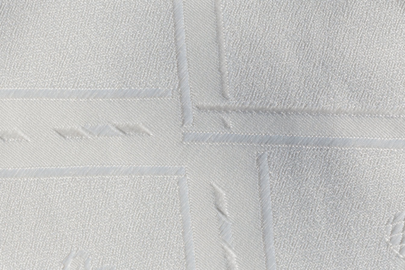 Close-up van een zuiver witte katoenen stof met geometrisch patroon
