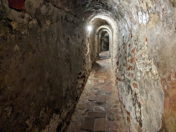 Medieval underground stone tunnel with light on the end of tunnel