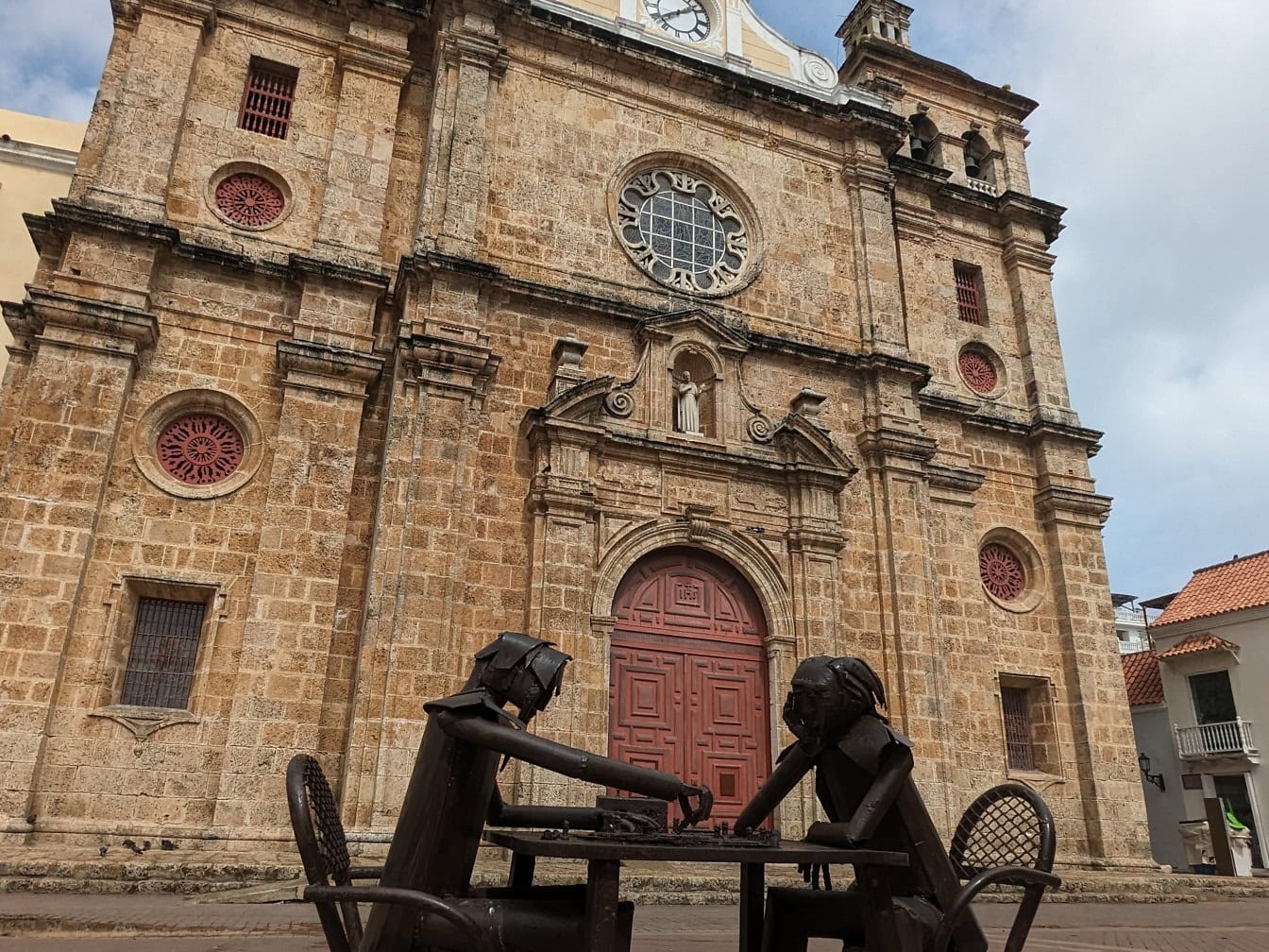 Socha dvoch ľudí sediacich pri stole a hrajúcich šach pred kostolom San Pedro Claver v Cartagene, Kolumbia