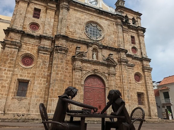 Socha dvou lidí sedících u stolu a hrajících šachy před kostelem San Pedro Claver v Cartageně v Kolumbii