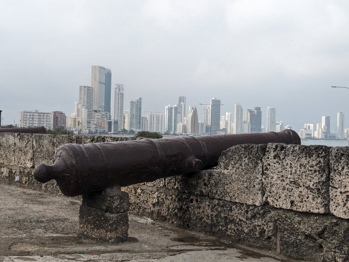 ปืนใหญ่ยุคกลางบนกําแพงหินที่มีเมือง Cartagena ในโคลัมเบียเป็นฉากหลัง