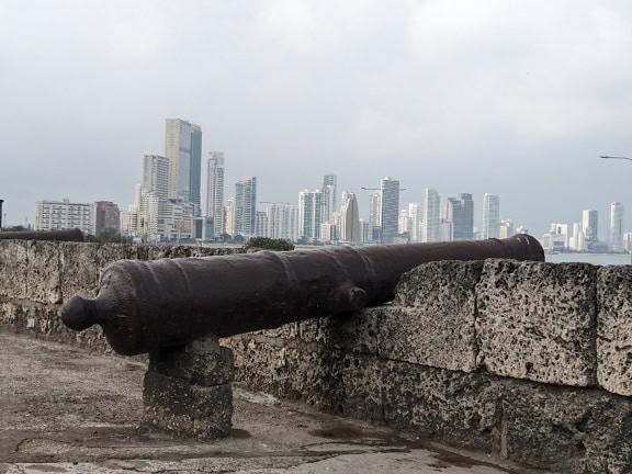 Medieval cannon on a stone wall with a city of Cartagena in Columbia in the background