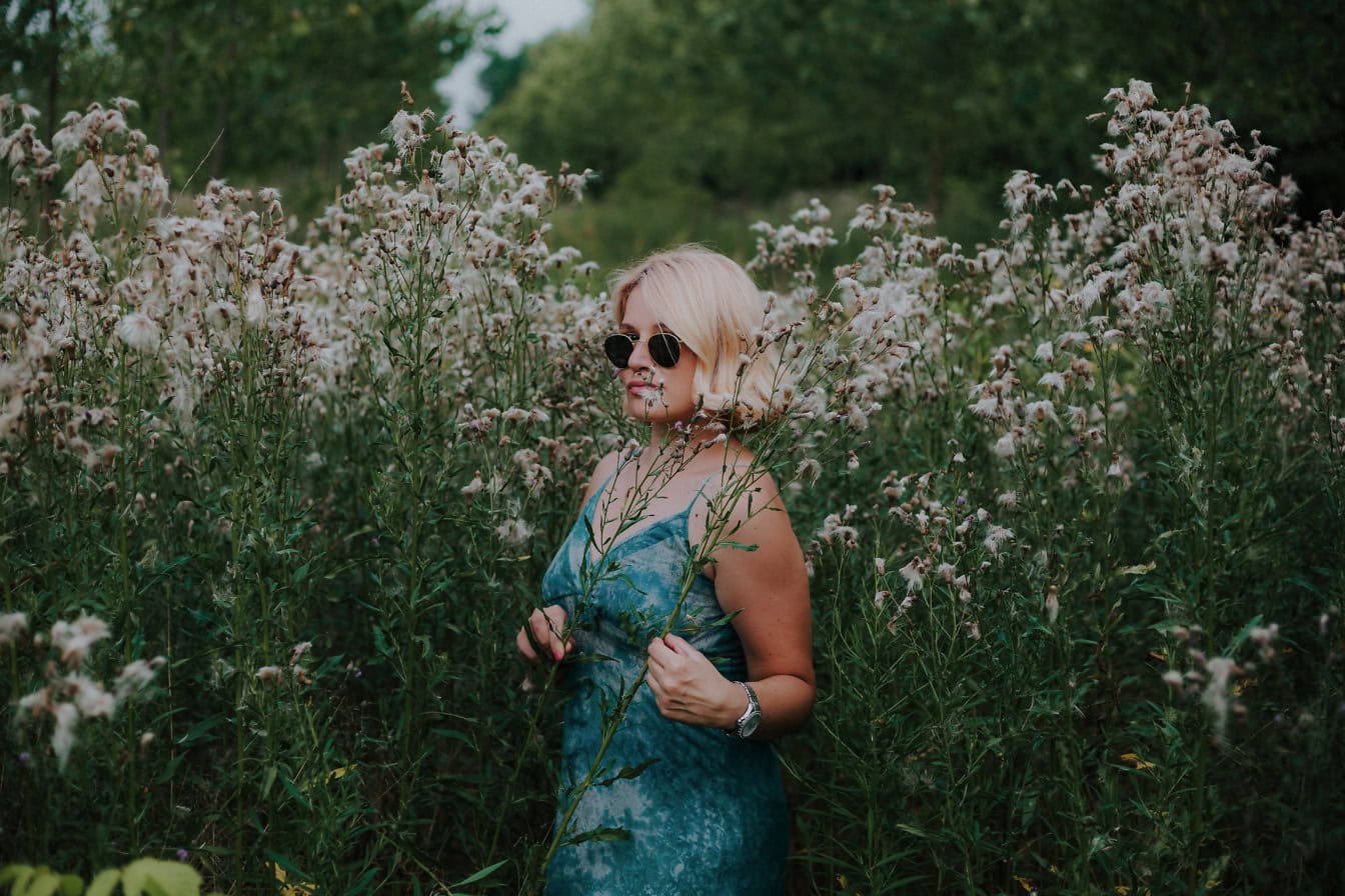 Femme blonde incroyablement attirante debout dans un champ de fleurs