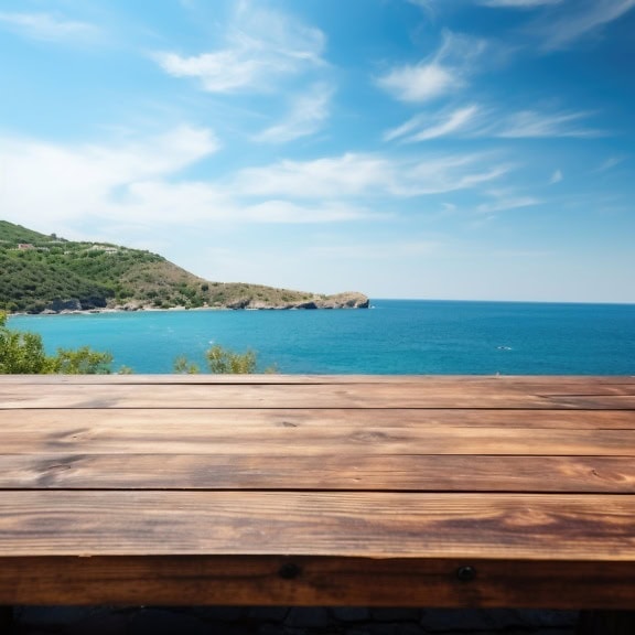 Close-up of a surface of a wooden table with a view of the ocean and hills