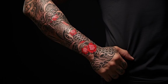 Man in darkness with beautiful Yakuza tattoo with red flowers on arm