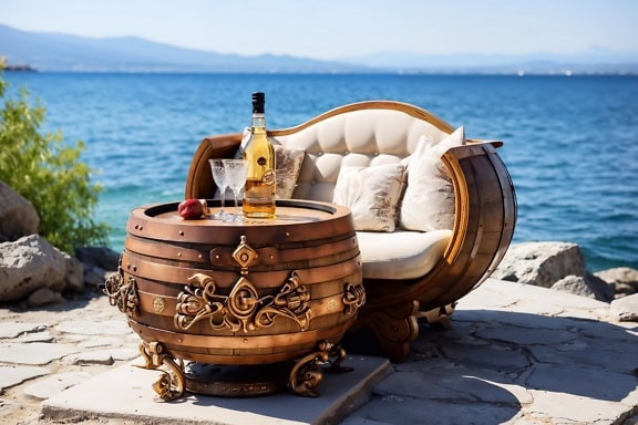 Rustikálna sudová pohovka a konferenčný stolík s fľašou bieleho vína a dvoma krištáľovými pohármi na pláži