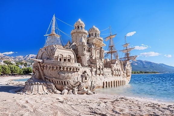Sand castle on the beach in the form of an old pirate sailing ship
