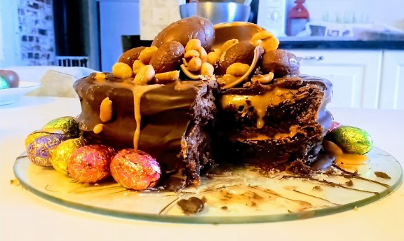 Вкусный шоколадный торт с орехами сверху и конфетами на тарелке