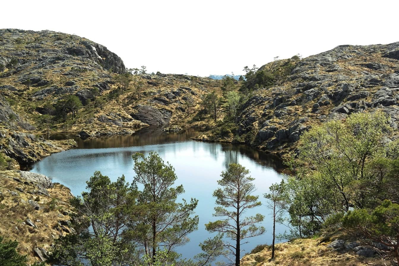 Landskab af søen omgivet af stenede bakker med en stille bjergatmosfære