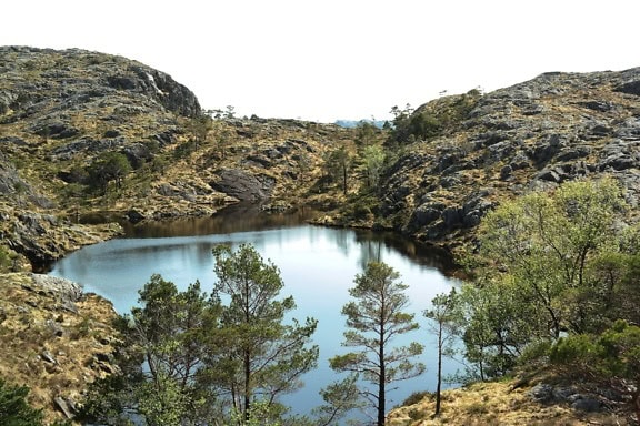 Krajina jezera obklopená skalnatými kopci s klidnou horskou atmosférou