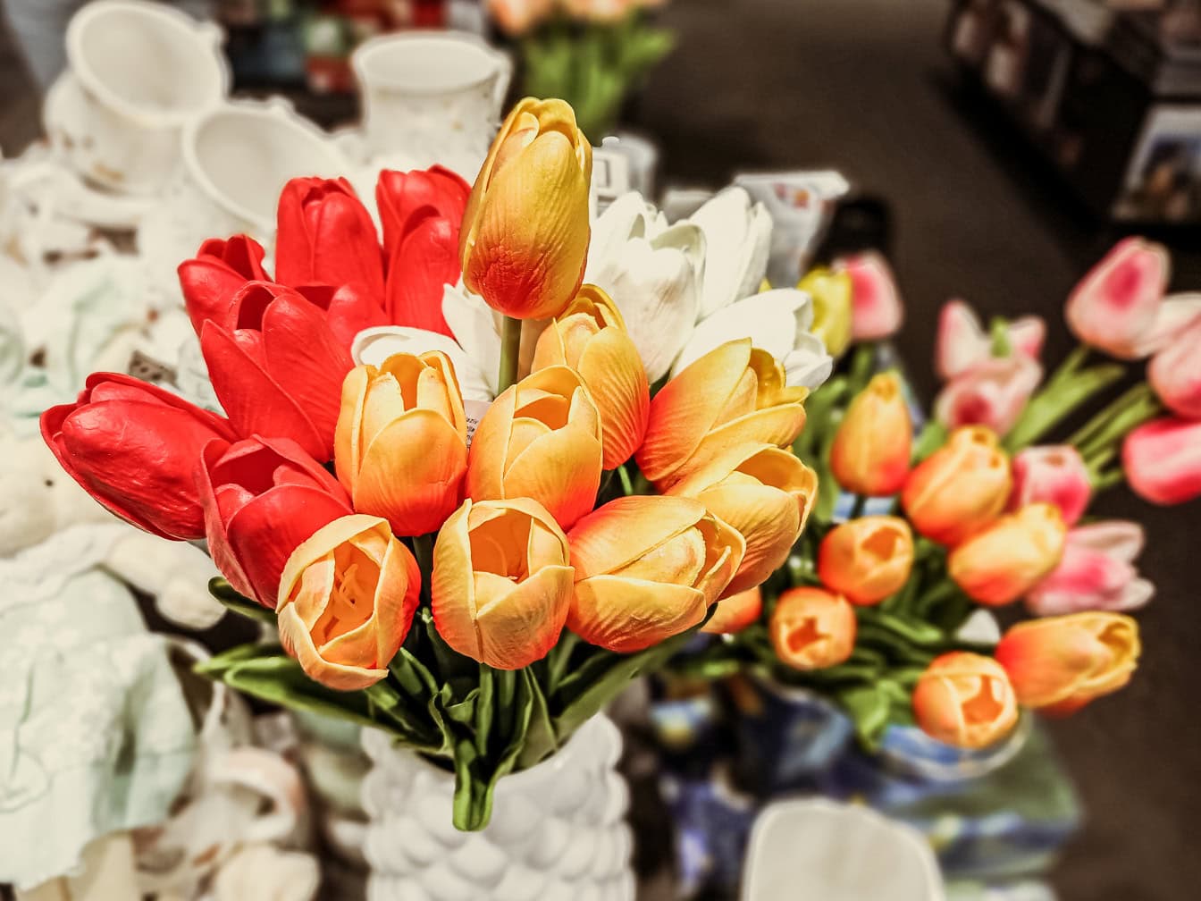 Kimppu muovisia oranssinkeltaisia tulppaanin kukkia myymälässä muun muassa