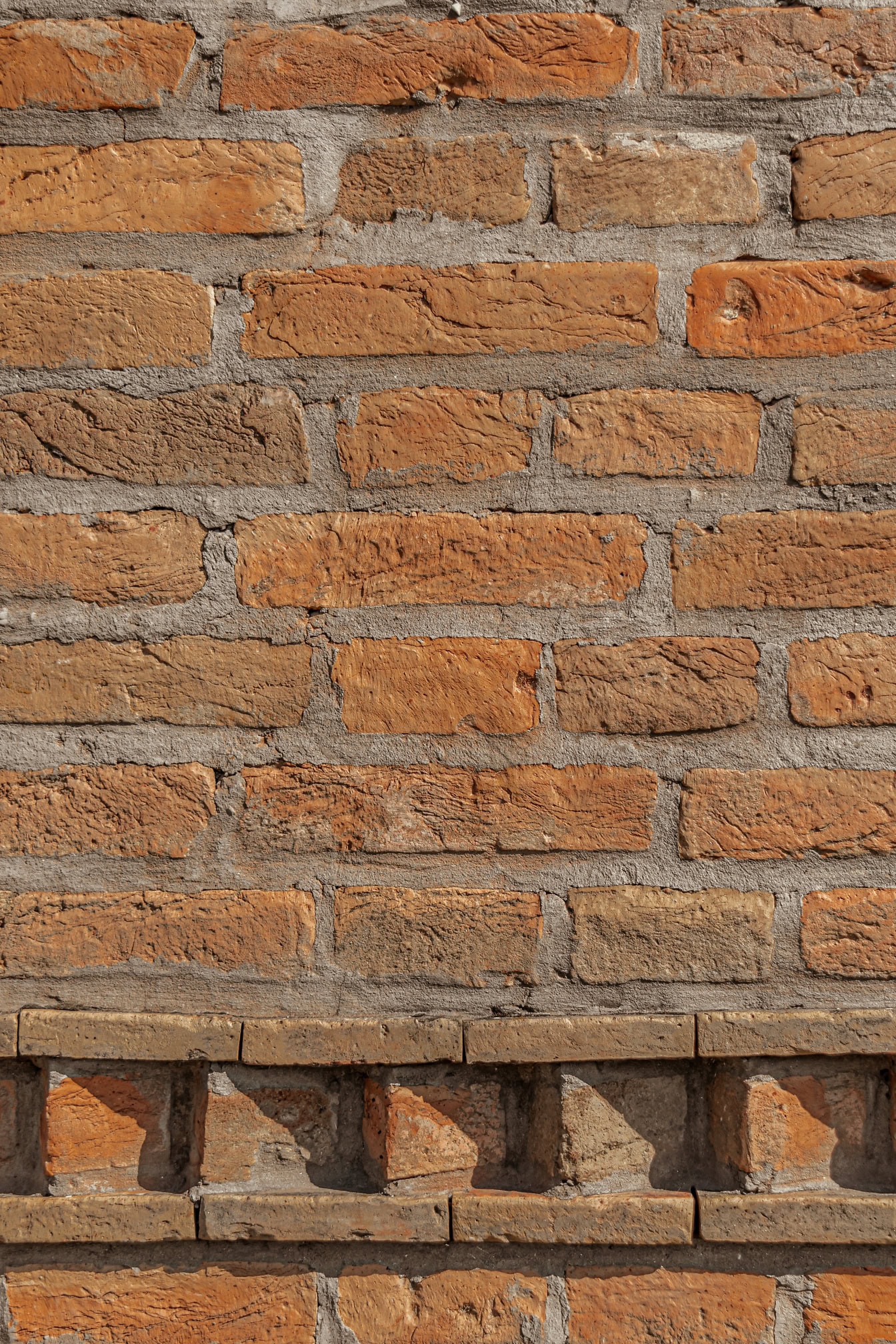 Texture of brick wall with thick cement layer between large format bricks and with horizontal decorative border at bottom