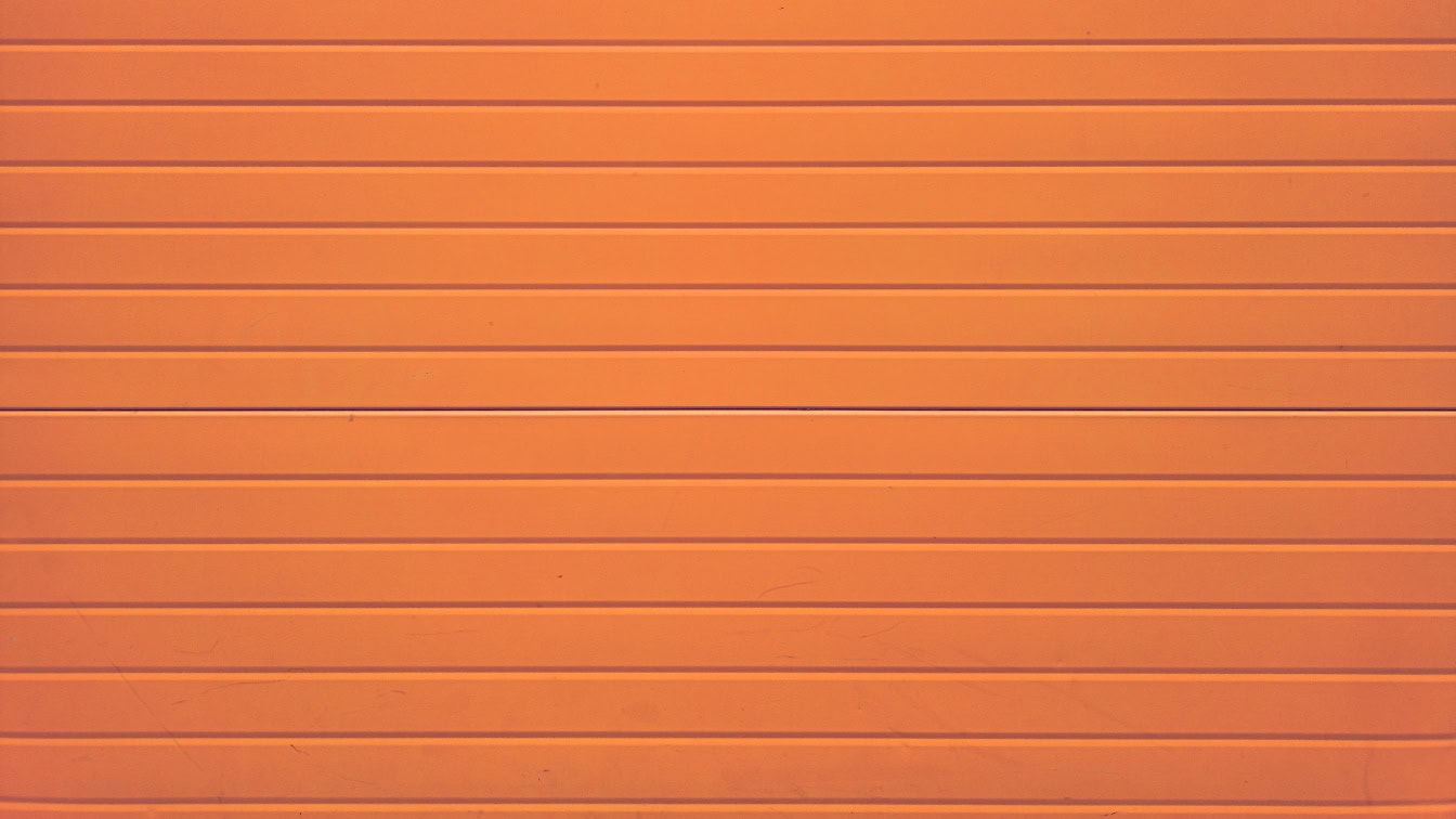 Texture di un pannello murale in legno dipinto arancione con assi impilate orizzontalmente