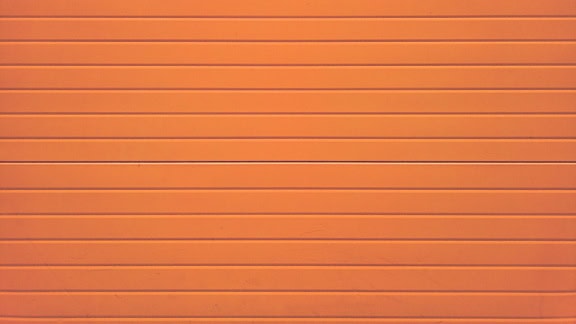 オレンジ色に塗装された木製の壁パネルと水平に積み上げられた板の質感