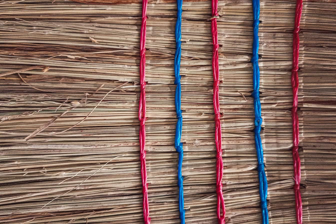 Primer plano de la textura de la superficie de la escoba de paja con cuerdas de nailon rojo oscuro y azul