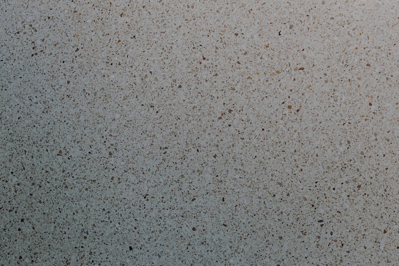 Tampilan close-up permukaan dinding beton dengan pecahan batu kecil