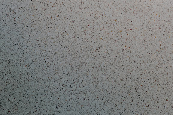 Detail povrchu betonové zdi s drobnými úlomky kamene