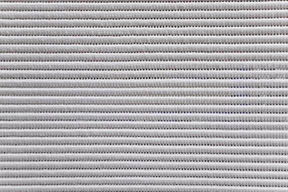 Tekstur kain spons putih keabu-abuan dengan garis-garis kecil yang terbuat dari lubang