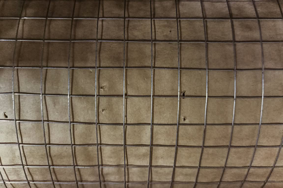 Malha de arame em uma superfície de papel marrom-claro enrolada