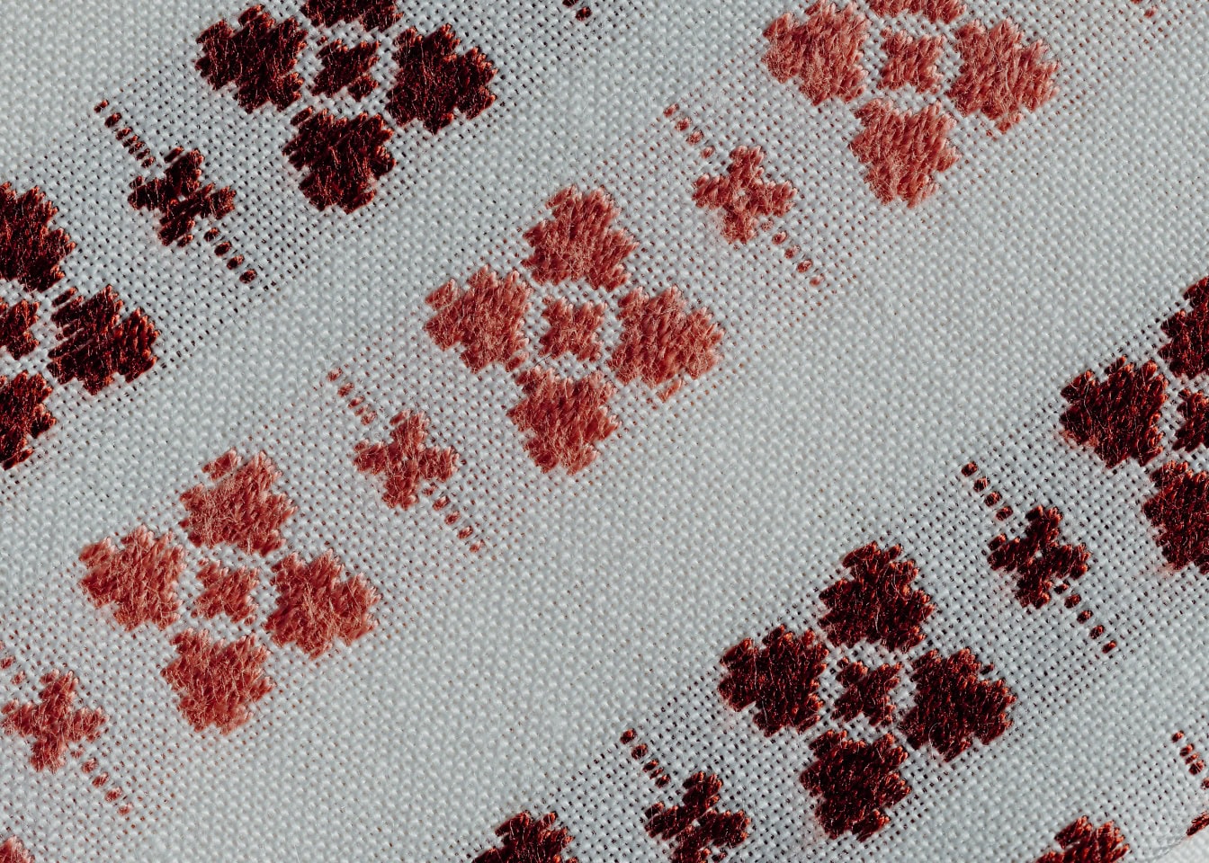 Prim-plan al unei țesături albe din bumbac cu motive tradiționale de culoare portocaliu-maro