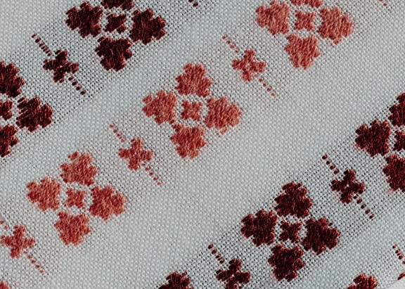 Krupni plan bijele pamučne tkanine s tradicionalnim motivima narančasto-smeđe boje