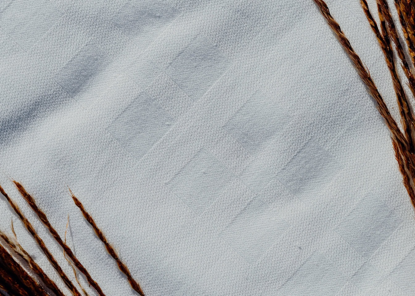 Close-up of a white cotton handkerchief with dark brown straws in corners