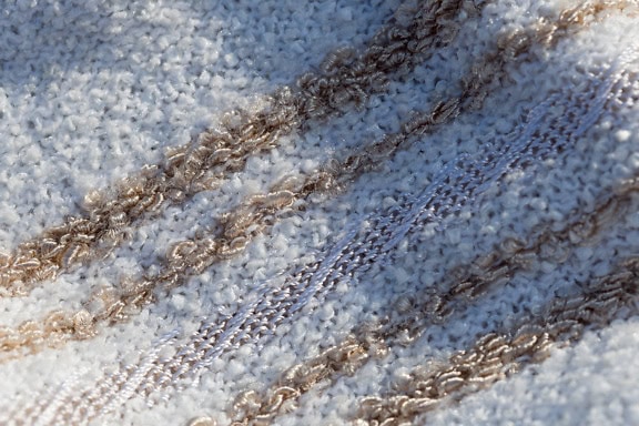 Zbliżenie tekstury białej bawełnianej tkaniny z błyszczącymi brązowymi liniami