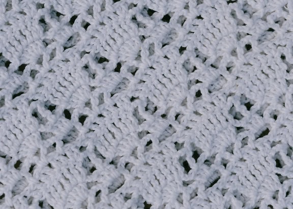 Prim-plan cu textura unei țesături tricotate albe lucrate manual