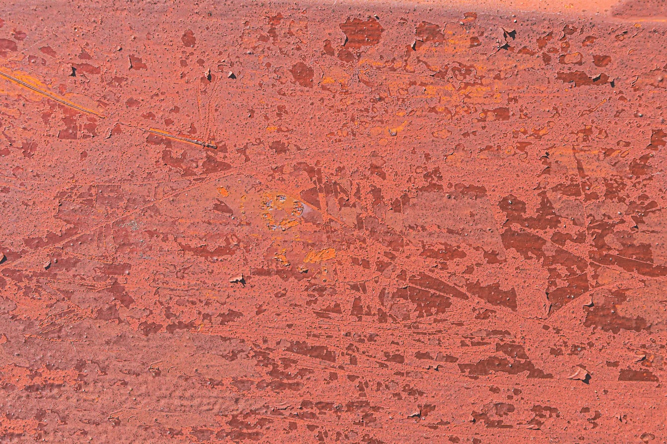 A rozsdás fémfelület textúrája vöröses festékkel, amely leválik