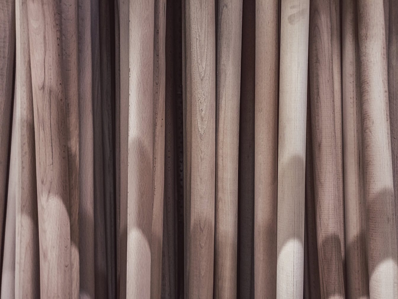 Trama di molti manici di legno impilati verticalmente con un’ombra su di essi