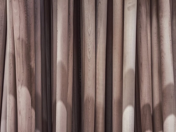 Texture of many vertically stacked wooden handles with a shadow on them
