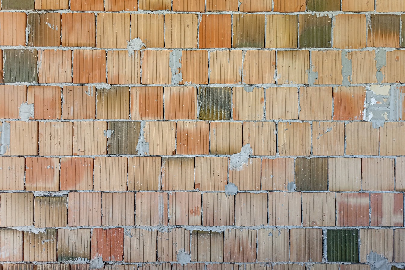 Væg af lysebrune firkantede blokke med nogle blokke med mørkegrøn glasur