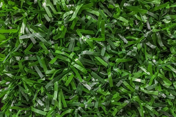 Zbliżenie tekstury sztucznej trawy wykonanej z zielonych pasków z tworzywa sztucznego z polichlorku winylu