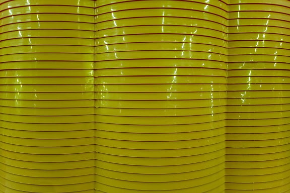 Texture of shining yellowish wavy plastic with horizontal lines