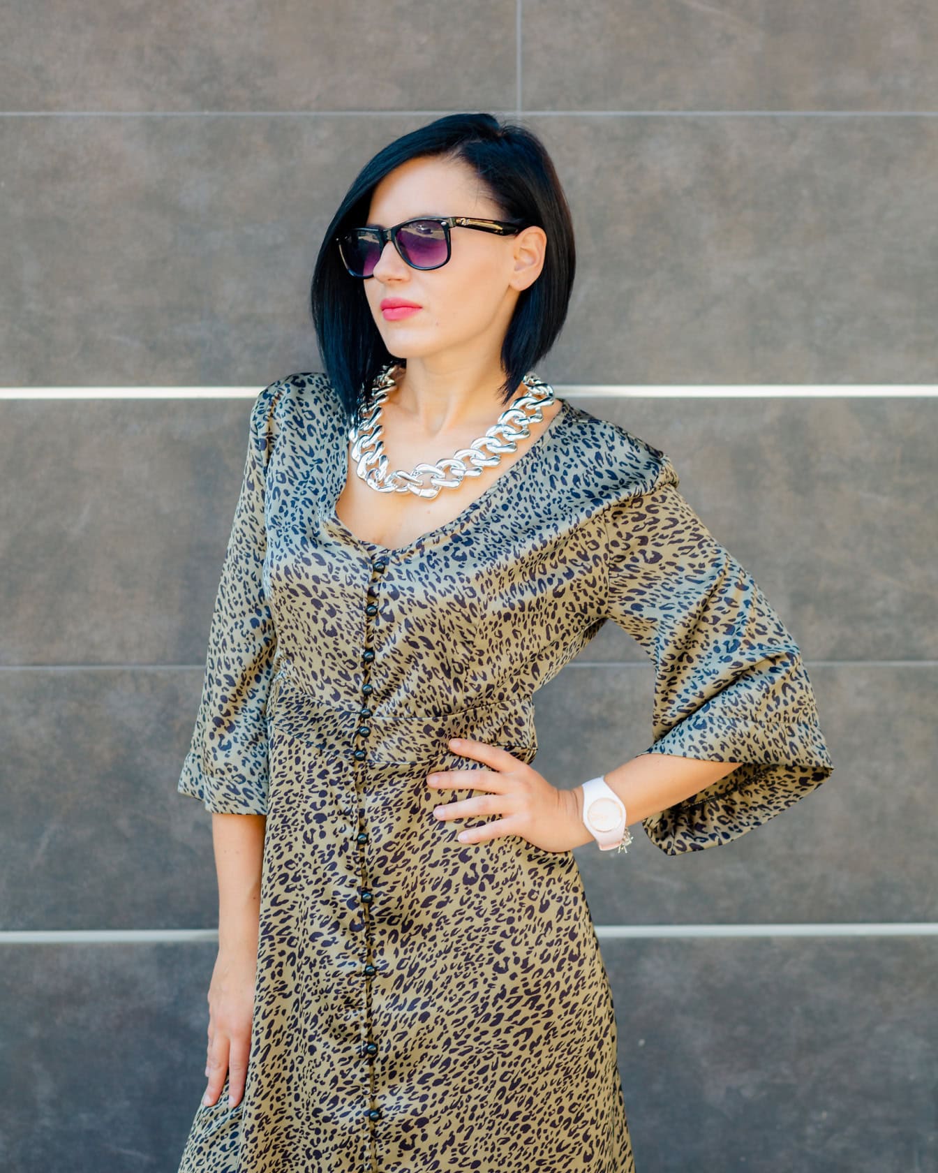 Žena pózuje v šatech s leopardím vzorem a slunečními brýlemi
