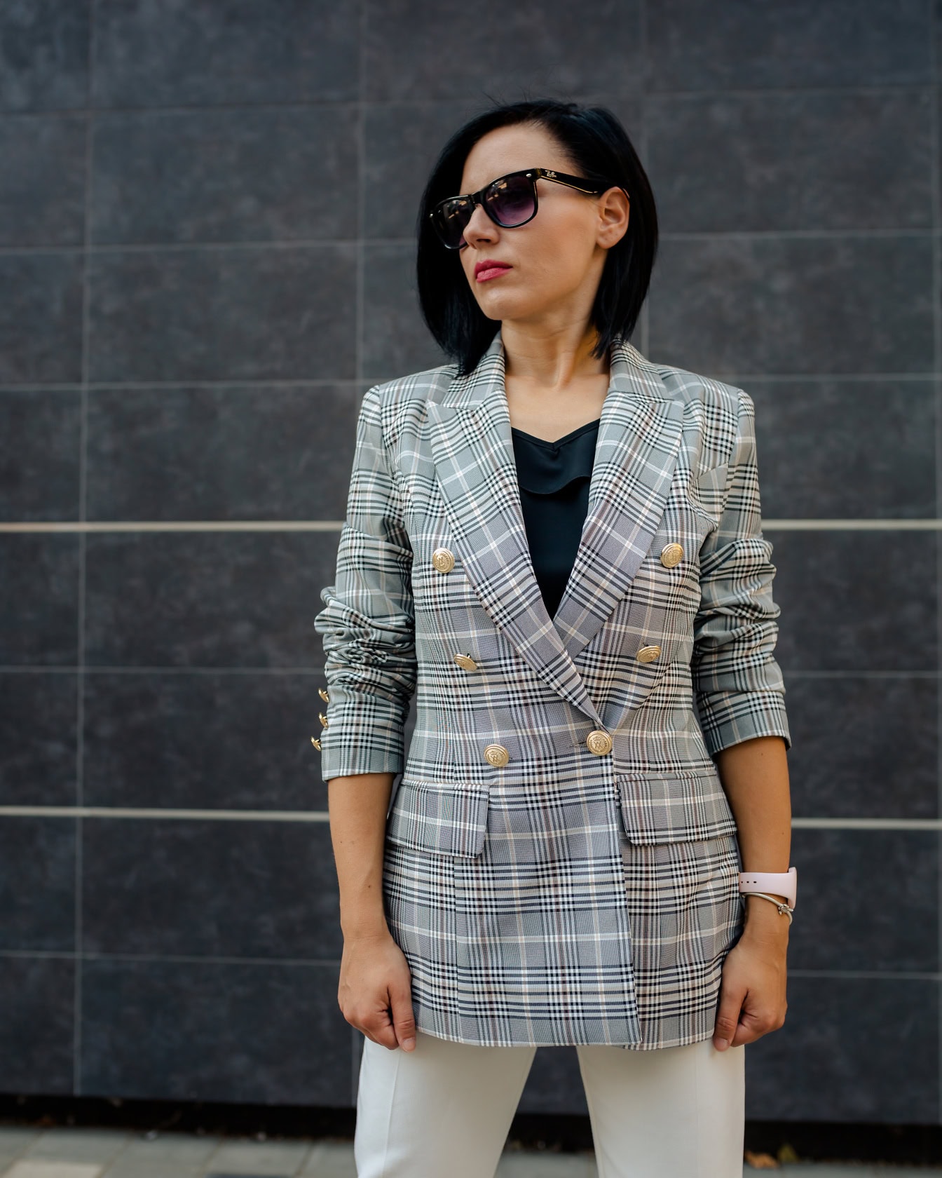 นักธุรกิจหญิงโพสท่าขณะสวมแว่นกันแดดและเสื้อเบลเซอร์ลายสก๊อต