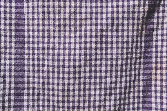 Tekstura fioletowo-białej tkaniny z pionowymi i poziomymi liniami tworzącymi małe kwadraty