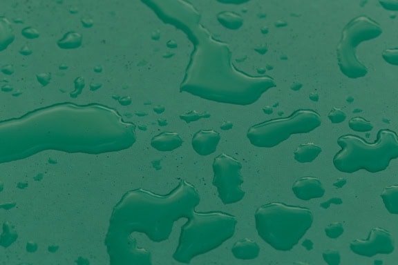 Gotas de agua sobre una superficie verde oscuro