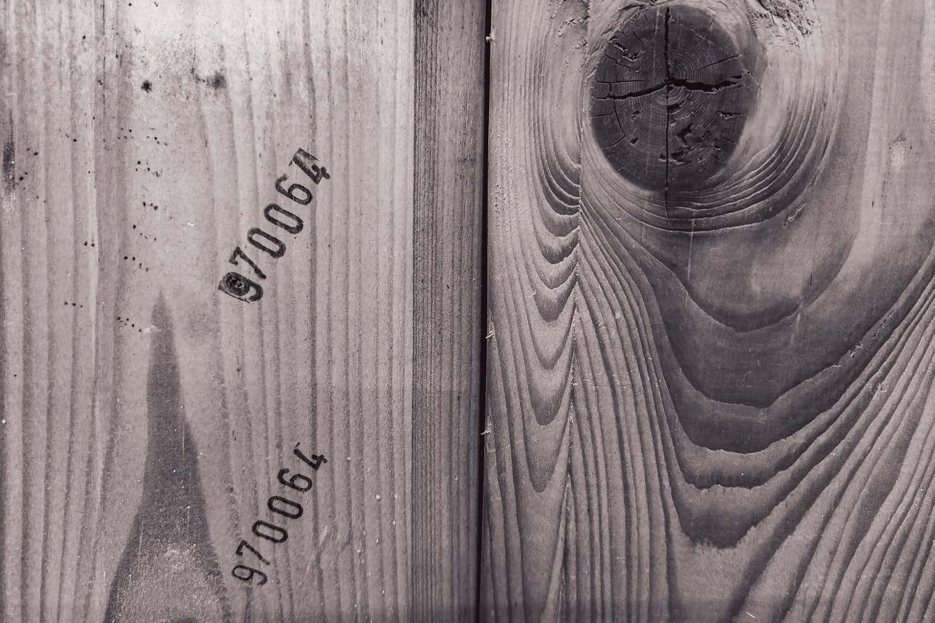 Tekstur af et træpanel med lodret stablede planker med knuder og industrielle markeringer med tal