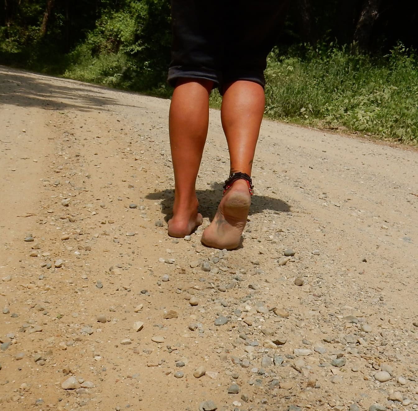Toprak yolda çıplak ayakla yürüyen adam